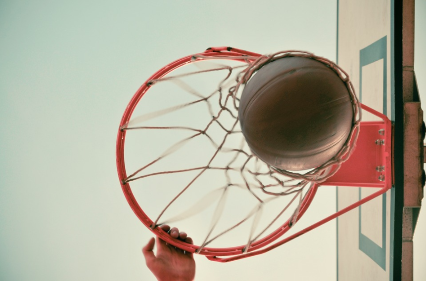 imagem aproximada de mão fechada na cesta enquanto a bola de basquete cai dela